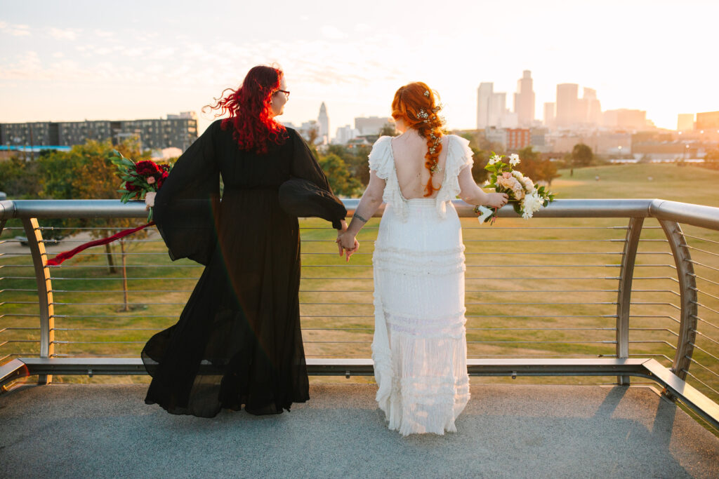 bride in black and bride in white at los angeles state park at sunset looking towards the city skyline los angels wedding photographer