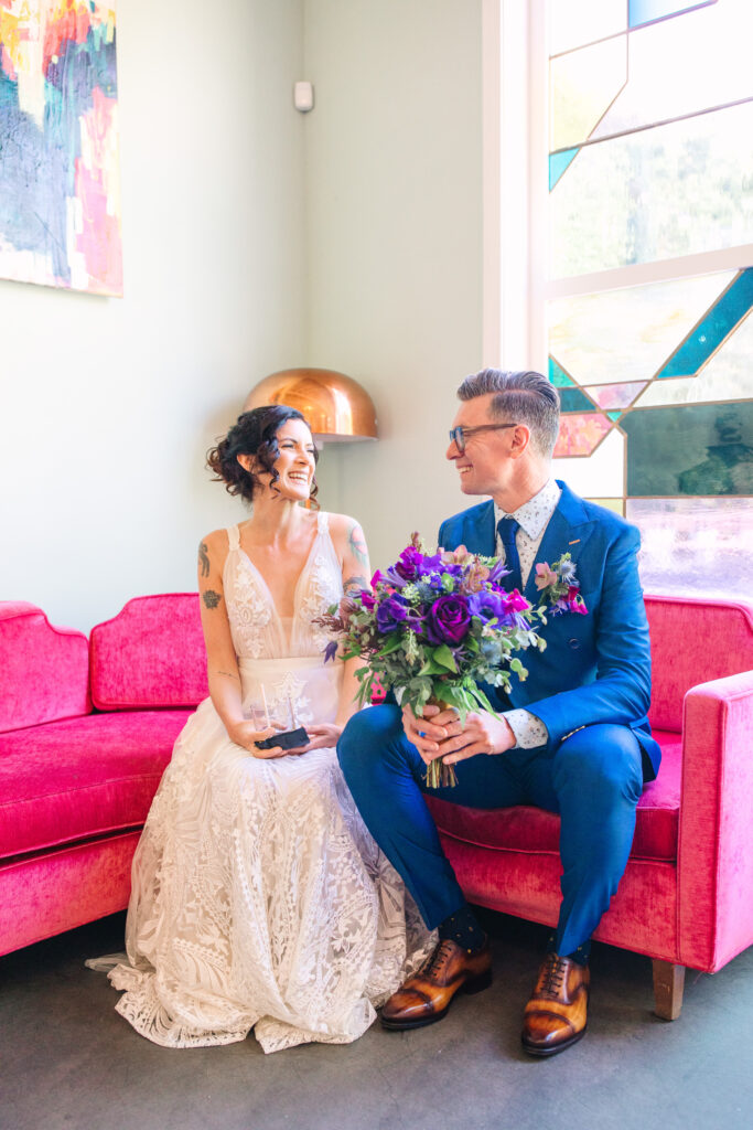 stress-free los angeles wedding, bride and groom sitting on a pink couch at the fig house with a purple bouquet.