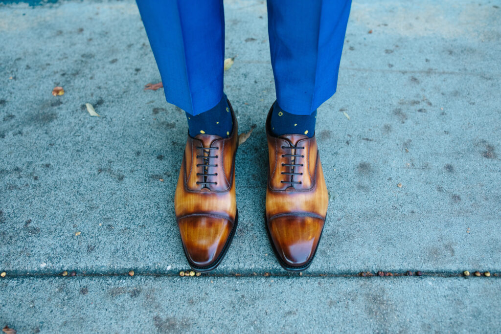 view of grooms shoes, groom's attire tiger eye dress shoes and blue suit and blue socks