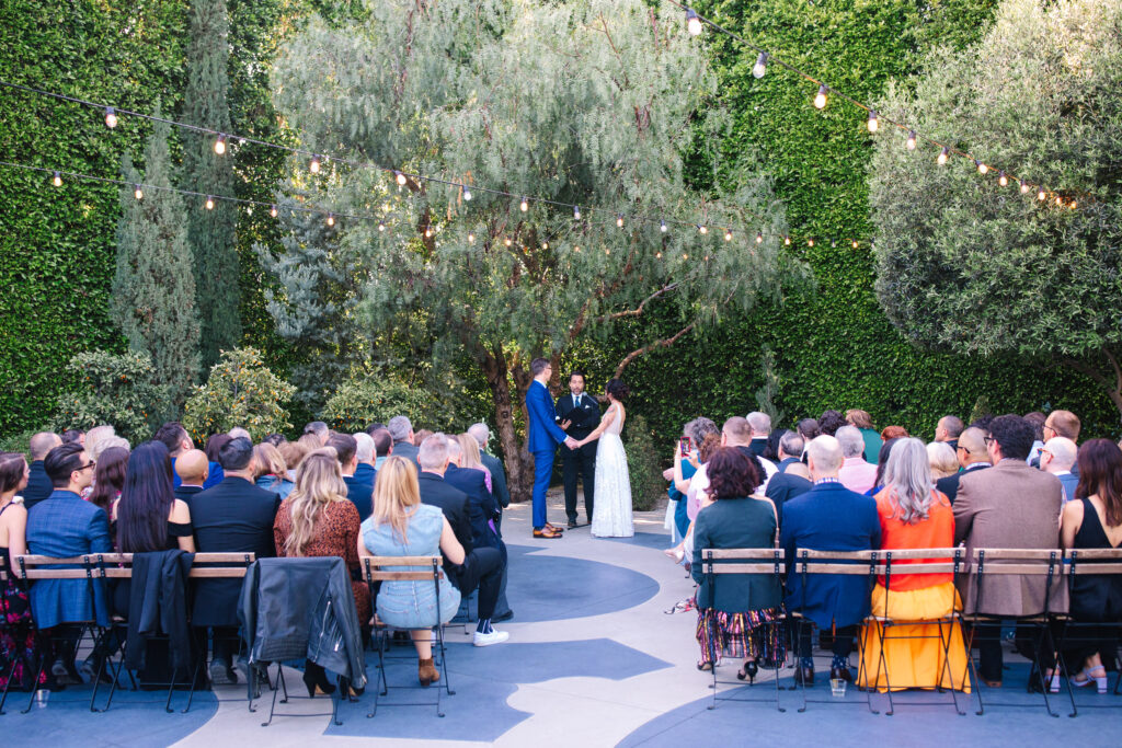 fig house wedding ceremony courtyard with bride and groom under pepper tree.