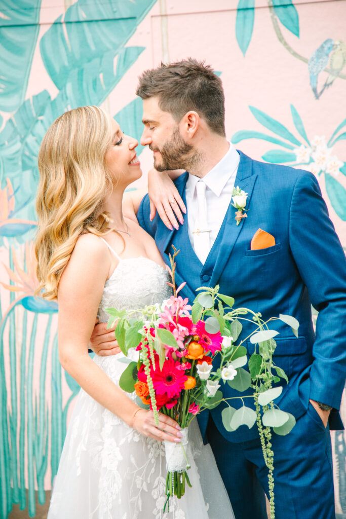 Candid Wedding Photography, bride and groom embracing, looking at each other, he's in a blue suit and she's in a white dress and is holding her bouquet.