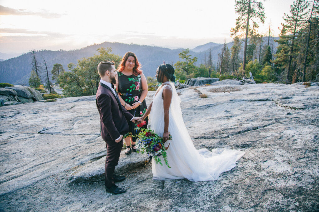 beetle rock elopement ceremony, elope in sequoia,  black bride in white wedding dress and groom in burgundy suit with officiant, sequoia wedding photographer, sequoia elopement photographer