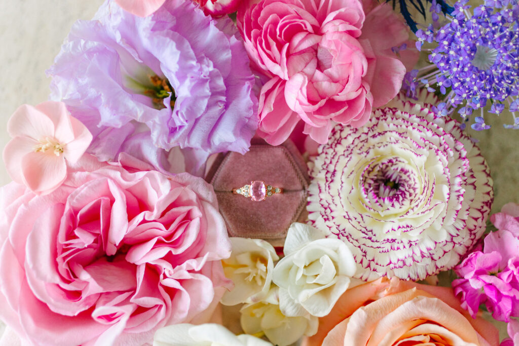 planning your Wedding, pink and purple flower flatlay with pink ring in pink ringbox in the center.