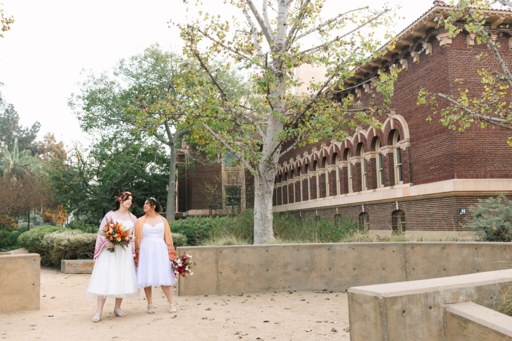 two brides in white wedding dresses outside of the natural history museum of los angeles, queer wedding photographer, lgbtq wedding photographer