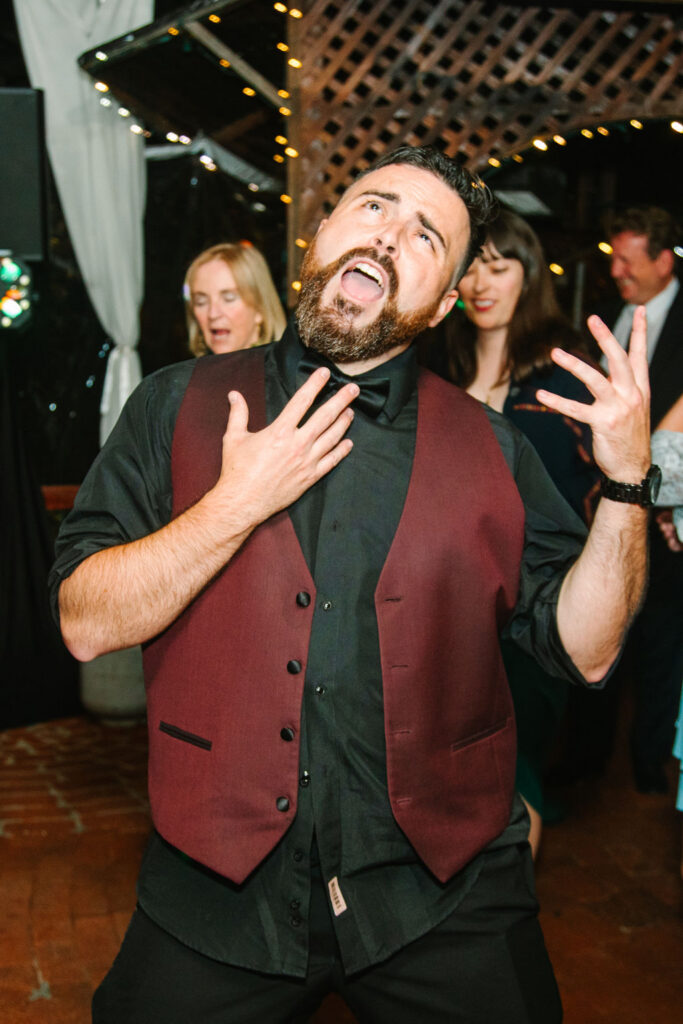 Inn of the Seventh Ray Wedding, Topanga Wedding Photographer, groom in black shirt and burgundy vest singing and dancing on the dance floor.