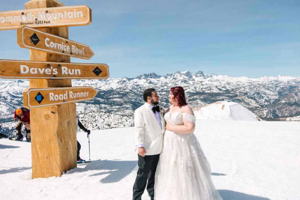 Mammoth wedding, lgbtq wedding photographer, queer wedding photographer, bride and groom at the top of mammoth mountain that is covered in snow just after their first look with the  minaret mountains in the background