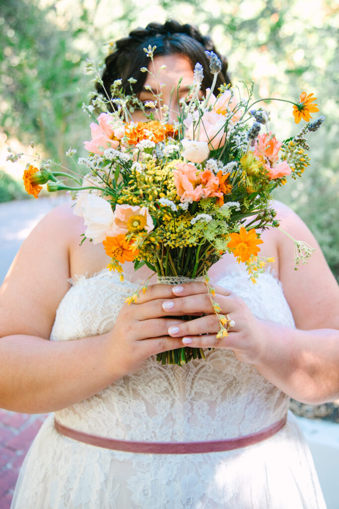 Lesbian Wedding, bride in a white dress, 1909 Wedding Venue, wildflower bouquet in front of bride's face.