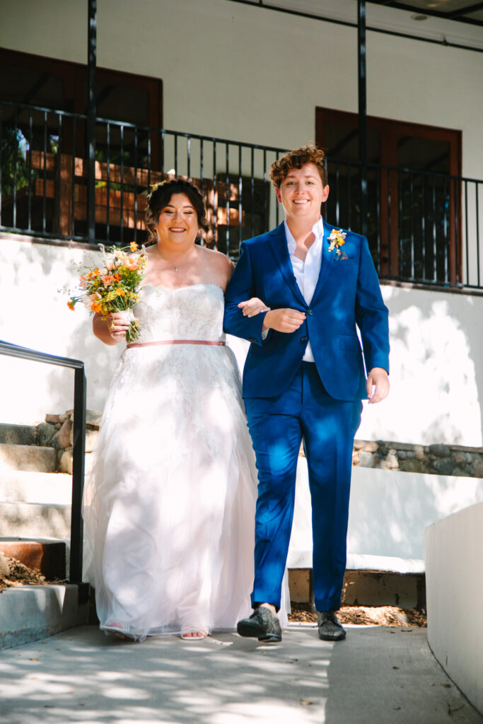 Lesbian Wedding Ceremony, one bride in a blue suit, one bride in a white dress, 1909 Wedding Venue 