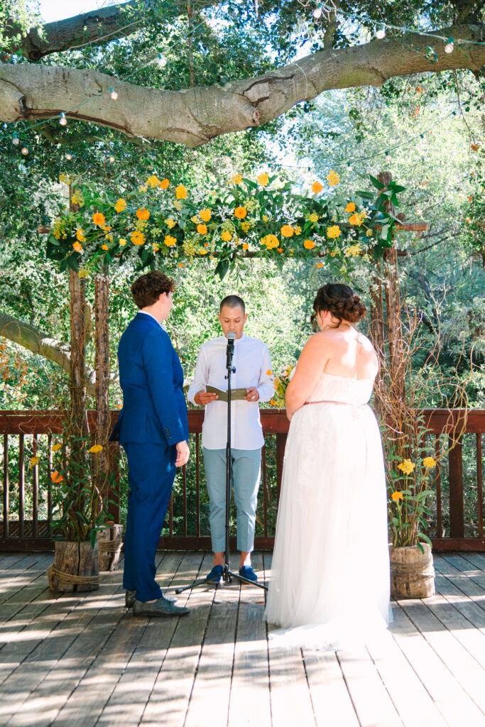 Lesbian Wedding Ceremony, one bride in a blue suit, one bride in a white dress, 1909 Wedding Venue 