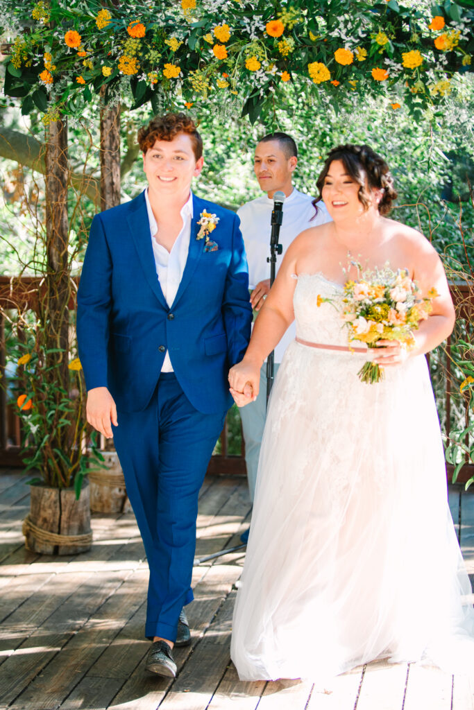 Lesbian Wedding Ceremony, one bride in a blue suit, one bride in a white dress, 1909 Wedding Venue 