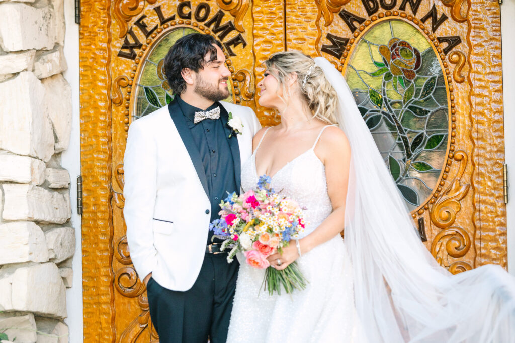 Madonna Inn Wedding Bride and Groom Portraits outside by the wooden and stained-glass doors.