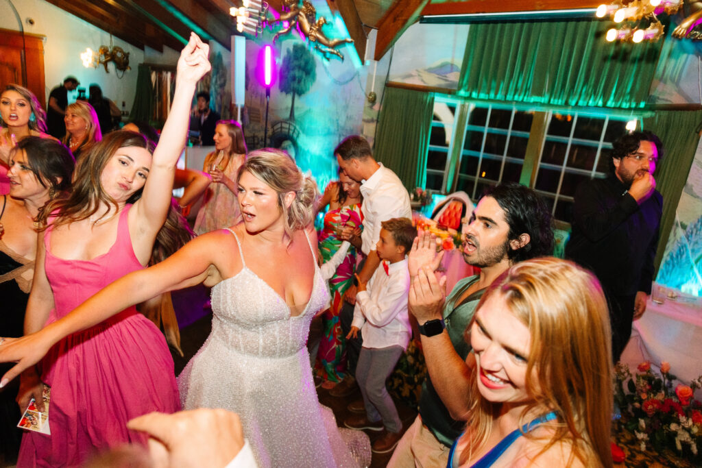 Madonna Inn Wedding Reception, people in bright colors dancing and having fun on the dance floor. Bride in sparkly wedding dress.