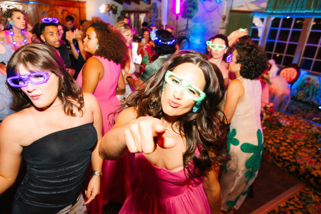 Madonna Inn Wedding  Reception, people in bright colors dancing and having fun on the dance floor. Bridesmaid in pink dress pointing at the camera