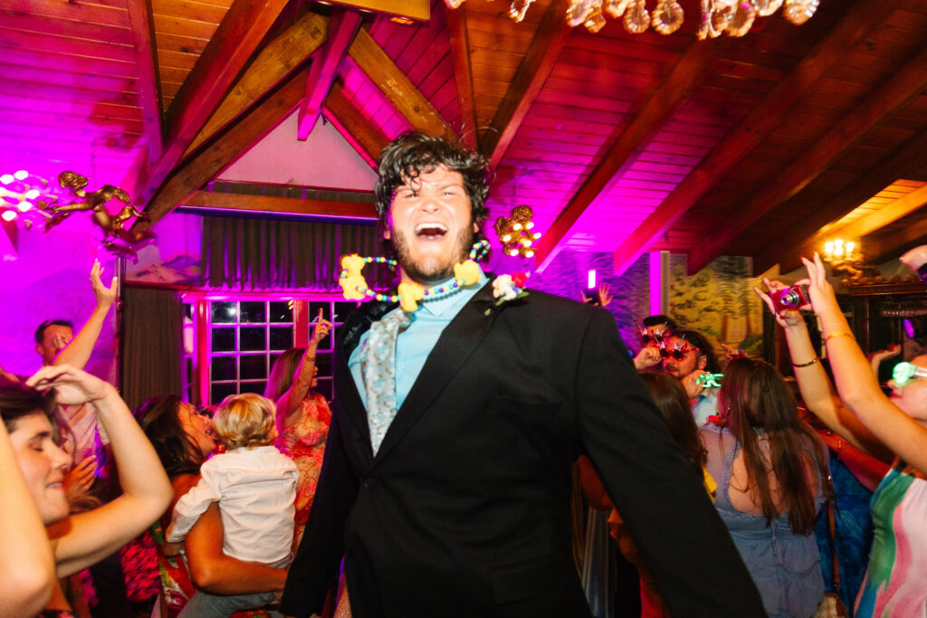 Madonna Inn Wedding Reception, people in bright colors dancing and having fun on the dance floor. Groomsman bouncing